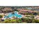 An aerial view shows a large community pool with lounge chairs, tropical trees, and manicured lawns at 20443 Cristoforo Pl, Venice, FL 34293