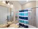 Bright bathroom featuring a vanity, tub and a tiled shower with a blue shower curtain at 20443 Cristoforo Pl, Venice, FL 34293