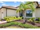 A meticulously landscaped home exterior boasts lush greenery and a decorative palm tree at 20443 Cristoforo Pl, Venice, FL 34293