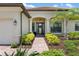 Charming home entrance with a brick walkway, lush landscaping, and decorative columns at 20443 Cristoforo Pl, Venice, FL 34293