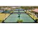 Aerial view of tennis courts featuring lush green landscaping, multiple courts, and beautiful neighborhood views at 20443 Cristoforo Pl, Venice, FL 34293
