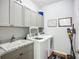 Well-equipped laundry room featuring gray cabinetry, granite countertops, a utility sink, and modern washer and dryer at 20749 Swallowtail Ct, Venice, FL 34293