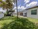 Spacious backyard featuring mature trees, a well-manicured lawn, and a comfortable patio area at 2245 Pickard Ln, North Port, FL 34286