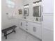 Bright bathroom with dual sink vanity, framed mirrors, white cabinets, marble floors, and bench at 2245 Pickard Ln, North Port, FL 34286