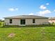 View of the backyard featuring a grassy lawn, fenced area, and the home's exterior with sliding glass door at 2355 Allsup Ter, North Port, FL 34286