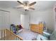 Bedroom with crib, rocker, ceiling fan, light green accent wall, and window letting in natural light at 2355 Allsup Ter, North Port, FL 34286