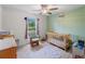 Bedroom with crib, rocker, ceiling fan, light green accent wall, and window letting in natural light at 2355 Allsup Ter, North Port, FL 34286