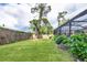 Spacious backyard with lush green lawn, mature trees, flowering bushes, and a screened lanai at 2445 Apache St, Sarasota, FL 34231