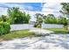Charming one-story home with a gravel driveway and white fence, surrounded by lush trees and greenery at 2445 Apache St, Sarasota, FL 34231