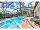 Sparkling pool and spa surrounded by a screened enclosure, lounge seating, and manicured landscaping at 2445 Apache St, Sarasota, FL 34231
