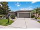 Charming home featuring a well-manicured lawn, mature trees, and a two-car garage on a sunny day at 24536 Buckingham Way, Port Charlotte, FL 33980
