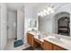 Well-lit main bathroom with double sinks, vanity space, large mirrors, and tiled walk-in shower at 24536 Buckingham Way, Port Charlotte, FL 33980
