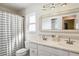 Bright bathroom with a double sink vanity, decorative mirror, and shower-tub combo at 2555 Yucca Rd, Venice, FL 34293