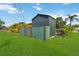 Backyard view featuring a spacious shed, lush lawn, and tropical foliage at 2555 Yucca Rd, Venice, FL 34293