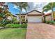 Attractive home featuring a tile roof, two-car garage, and brick paved driveway with tropical landscaping at 257 Teramo Way, Nokomis, FL 34275