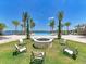 Outdoor fire pit area surrounded by chairs, lush lawn, and lake views at 257 Teramo Way, Nokomis, FL 34275