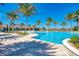 Resort-style pool with palm trees, sun loungers, and beautiful clubhouse in a tropical community at 257 Teramo Way, Nokomis, FL 34275