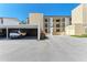 Exterior shot of the condo building featuring a covered parking area and well-maintained landscaping at 2718 Orchid Oaks Dr # C-202, Sarasota, FL 34239