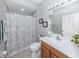 Well-lit bathroom with a vanity, toilet, shower with patterned curtain and decorative wall art at 29704 Niagara Court, Englewood, FL 34223