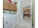 Functional laundry room with washer, dryer, and wooden storage cabinets at 29704 Niagara Court, Englewood, FL 34223
