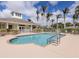 Community pool surrounded by palm trees, lounge chairs, and a white fence at 29704 Niagara Court, Englewood, FL 34223