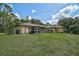 Backyard view of the home with a screened in patio and a well maintained lawn at 3199 Elkrem Ave, North Port, FL 34286