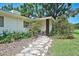 Charming single-story home featuring a stone walkway and a cozy front porch nestled amidst lush landscaping at 3340 Webber St, Sarasota, FL 34239