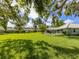 Expansive backyard with lush green grass, mature trees, and an inviting outdoor seating area at 337 Meadow Beauty Ct, Venice, FL 34293
