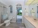 Bright bathroom with a shower, toilet, vanity, and an open door to the outside at 337 Meadow Beauty Ct, Venice, FL 34293
