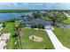 Waterfront single-Gathering home boasts a two-car garage, well-kept lawn, mature palms, and water access on a sunny day at 3376 Peace River Dr, Punta Gorda, FL 33983
