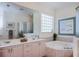 Bright bathroom with dual sinks, large mirror, soaking tub and glass block window at 4308 Via Del Santi, Venice, FL 34293