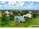 Aerial view of a home with teal roof, pool and screened lanai surrounded by lush landscaping and green grass at 467 Sherbrooke Ct, Venice, FL 34293