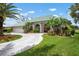 A well manicured lawn and landscaping leads up to a cream colored home with a teal roof and a brick colored front door at 467 Sherbrooke Ct, Venice, FL 34293