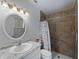 Nicely renovated bathroom featuring marble countertops, and a shower with brown tiles at 4688 Maraldo Ave, North Port, FL 34287