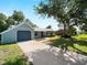 Quaint single-story home featuring an attached garage, metal roof, and mature trees at 4688 Maraldo Ave, North Port, FL 34287