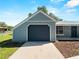Attached garage with a paved driveway leading up to a well-maintained blue house with a metal roof at 4688 Maraldo Ave, North Port, FL 34287