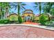 Beautiful clubhouse with manicured landscaping, tall palm trees, and red brick walkway entrance at 5459 Bentgrass Dr # 2-304, Sarasota, FL 34235