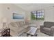 Cozy living room with a comfortable sectional, neutral decor, and large windows at 5459 Bentgrass Dr # 2-304, Sarasota, FL 34235