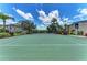 Community tennis court surrounded by green space, lush landscaping, and blue skies at 5459 Bentgrass Dr # 2-304, Sarasota, FL 34235