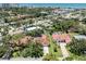 Aerial view of a home highlighting the tile roof, driveway, and surrounding lush greenery near the ocean at 609 Madrid Ave, Venice, FL 34285