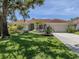 Charming single-story home with a well-manicured lawn and a tile roof, complemented by mature trees and lush landscaping at 609 Madrid Ave, Venice, FL 34285