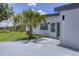 Backyard view with a palm tree, painted patio, manicured lawn, and modern white home exterior at 6821 Marius Rd, North Port, FL 34287