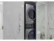 Bathroom closet with a stacked washer and dryer, marble-style tiling, and gold fixtures at 6821 Marius Rd, North Port, FL 34287