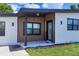 Welcoming front porch with a sleek, contemporary design, wood-look accent wall, and modern lighting at 6821 Marius Rd, North Port, FL 34287