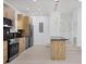 Modern kitchen with wood-look cabinetry, black countertops, stainless-steel appliances, and stylish pendant lighting at 6821 Marius Rd, North Port, FL 34287
