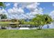 Scenic backyard with green lawn and canal views with wooden dock on the waterfront, perfect for relaxation at 6821 Marius Rd, North Port, FL 34287