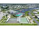 Aerial view of community amenities including shuffleboard courts, community pool and clubhouse near a marina and canal at 738 Riverview Cir, North Port, FL 34287