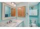 Bright blue bathroom with marble countertops, decorative mirror, and plenty of cabinet space at 738 Riverview Cir, North Port, FL 34287