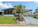 Charming single-story home with a well-manicured lawn, palm tree, carport, and screened-in porch at 738 Riverview Cir, North Port, FL 34287
