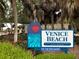 Scenic entrance sign to Venice Beach with palm trees, stone wall, and inviting landscape at 751 Capri Isles Blvd # 108, Venice, FL 34292